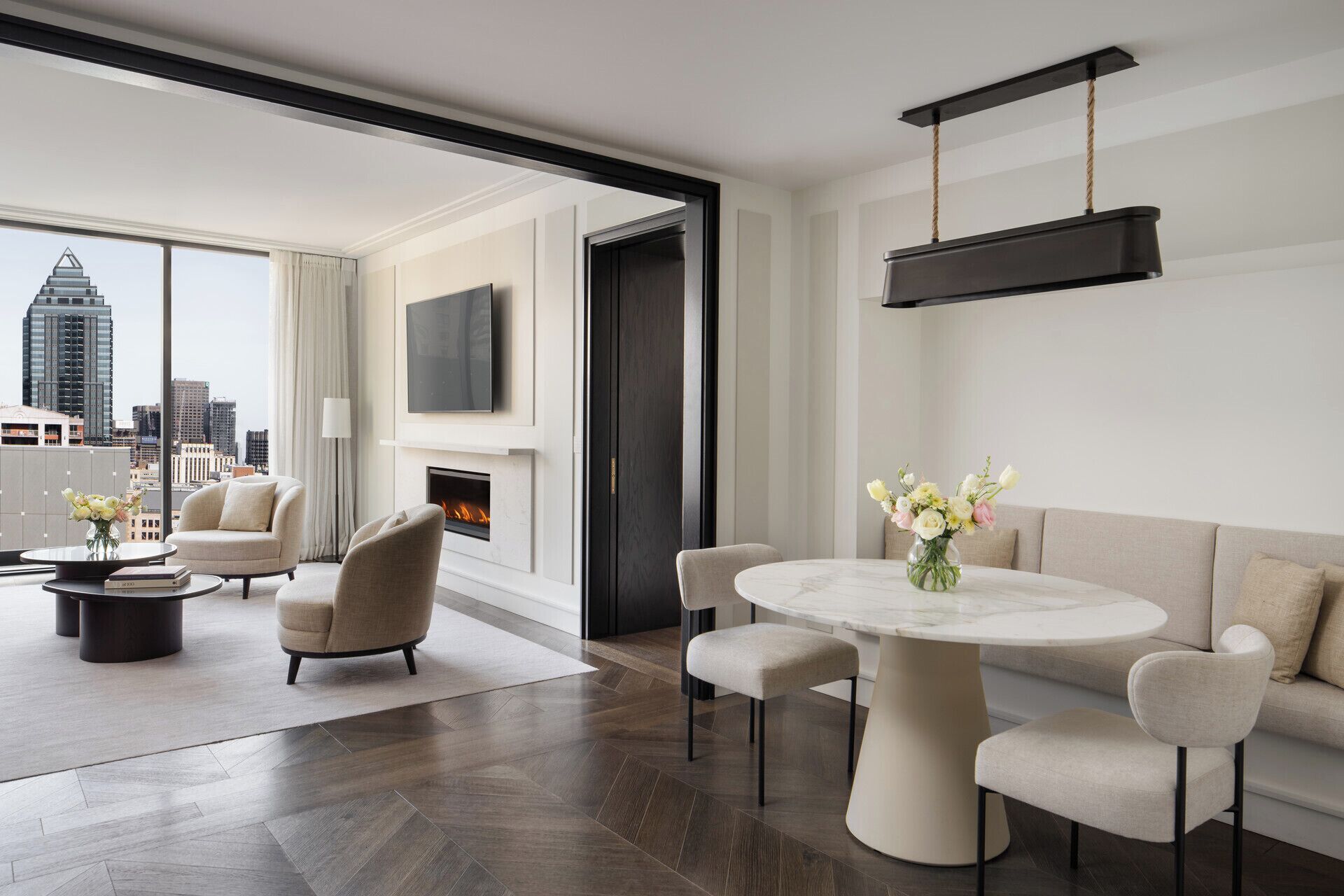 Een moderne woonkamer met een open haard, een ronde eettafel en een bank.