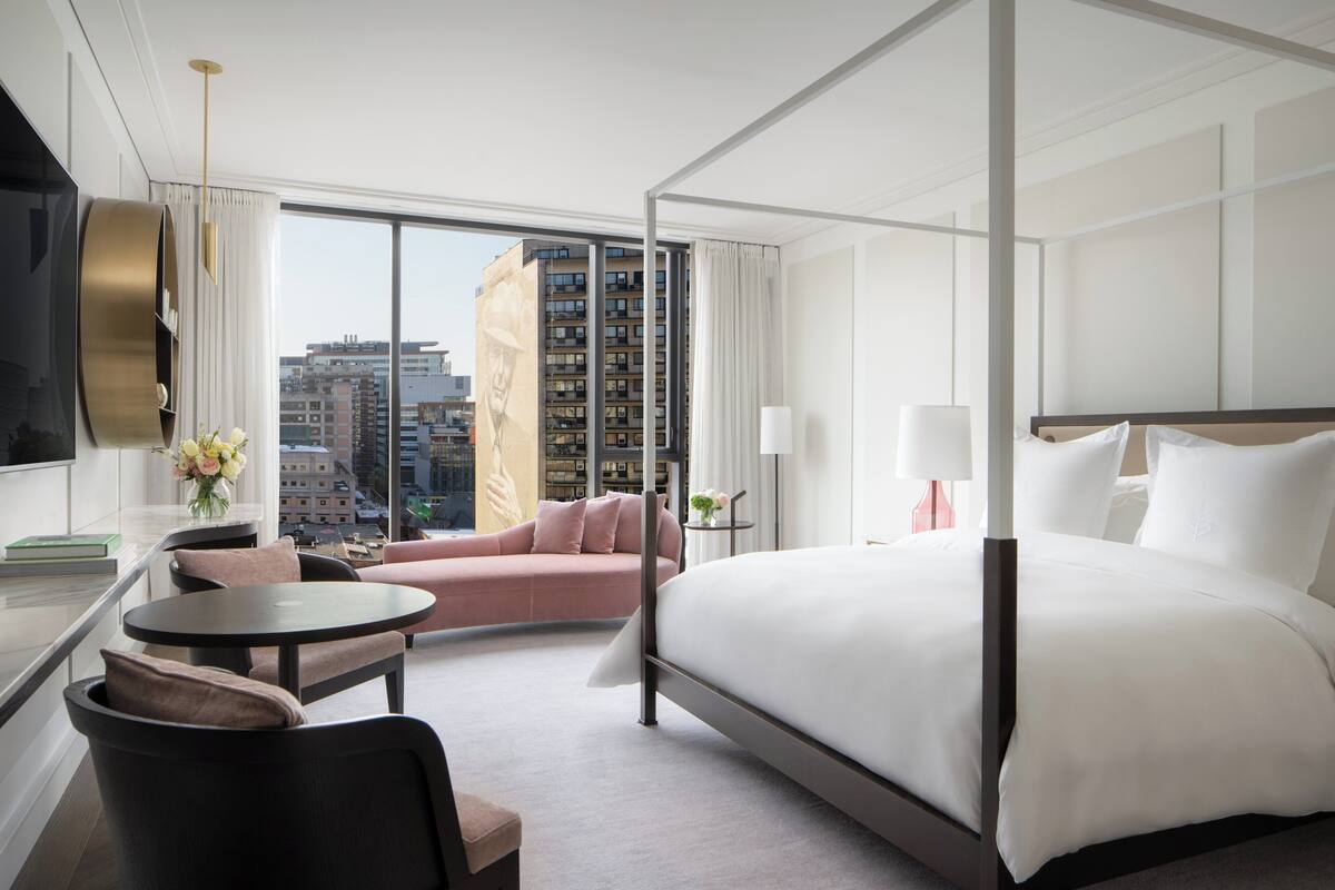 Una habitación de hotel moderna con una cama grande, un sofá, una mesa redonda y un televisor.