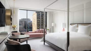 Una habitación de hotel moderna con una cama grande, un sofá, una mesa redonda y un televisor.
