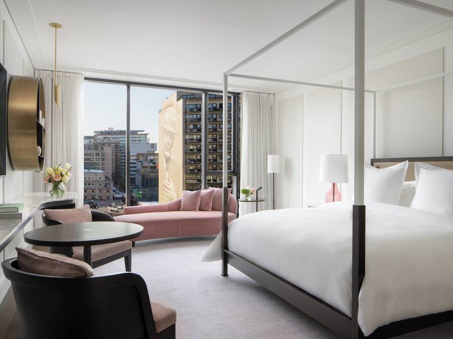 Una habitación de hotel moderna con una cama grande, un sofá, una mesa redonda y un televisor.