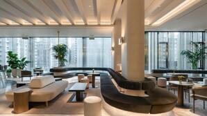 A modern lounge area with a curved sofa, round tables, and potted plants. - Four Seasons Hotel Montreal (Montreal)