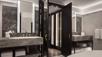 Un baño moderno con dos lavamanos de mármol, un espejo grande y una ducha a ras de suelo.