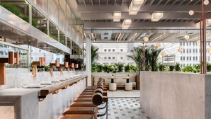 A modern restaurant with a long counter, cushioned seating, and a view of the cityscape. - Four Seasons Hotel Montreal (Montreal)
