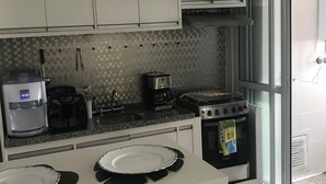 A modern kitchen with white cabinets, a coffee maker, a toaster, and a stove. - Ap Brás Templo Salomão 25 Março (São Paulo)