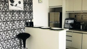 A modern kitchen with a geometric-patterned backsplash, a stainless steel refrigerator, and a coffee machine. - Ap Brás Templo Salomão 25 Março (São Paulo)