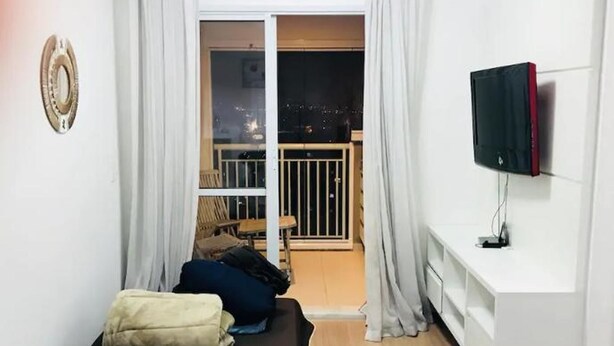 A compact living space with a balcony, a sofa, a TV, and a white console. - Ap Brás Templo Salomão 25 Março (São Paulo)