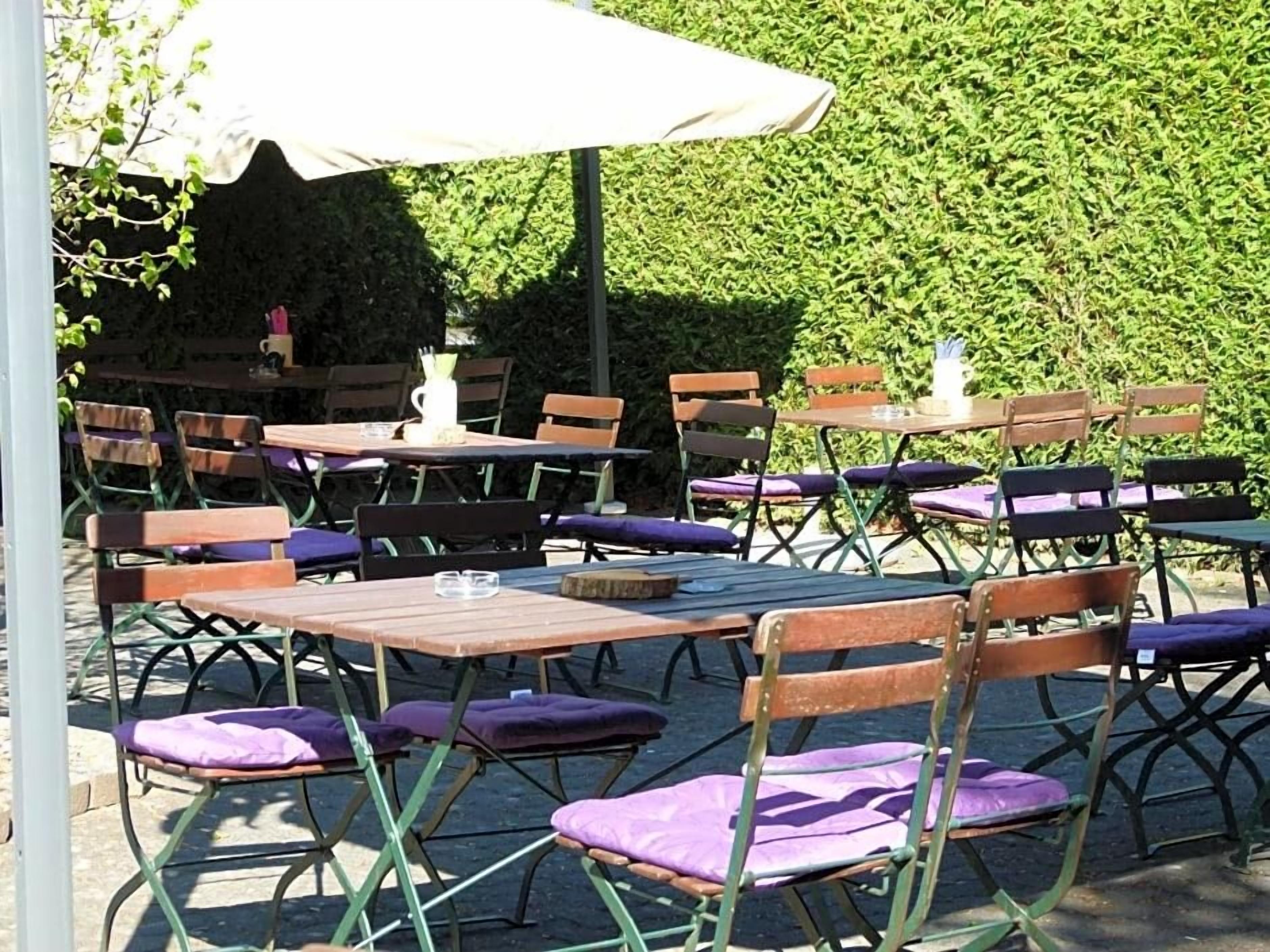 Un espace extérieur aménagé avec plusieurs tables et chaises, dont certaines sont dotées de parasols.