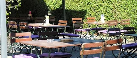 An outdoor seating area with multiple tables and chairs, some with umbrellas.