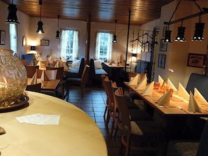 Un restaurante acogedor con mesas y sillas de madera, y lámparas colgantes.