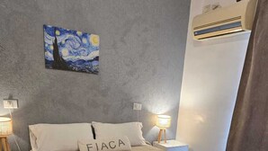 Ein Schlafzimmer mit einem Bett, zwei Nachttischen, einer Klimaanlage und einem Bild an der Wand.