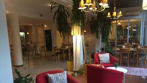 Ein modernes Interieur mit roten Armlehnstühlen, einer großen Stehlampe und topfgepflanzten Pflanzen.