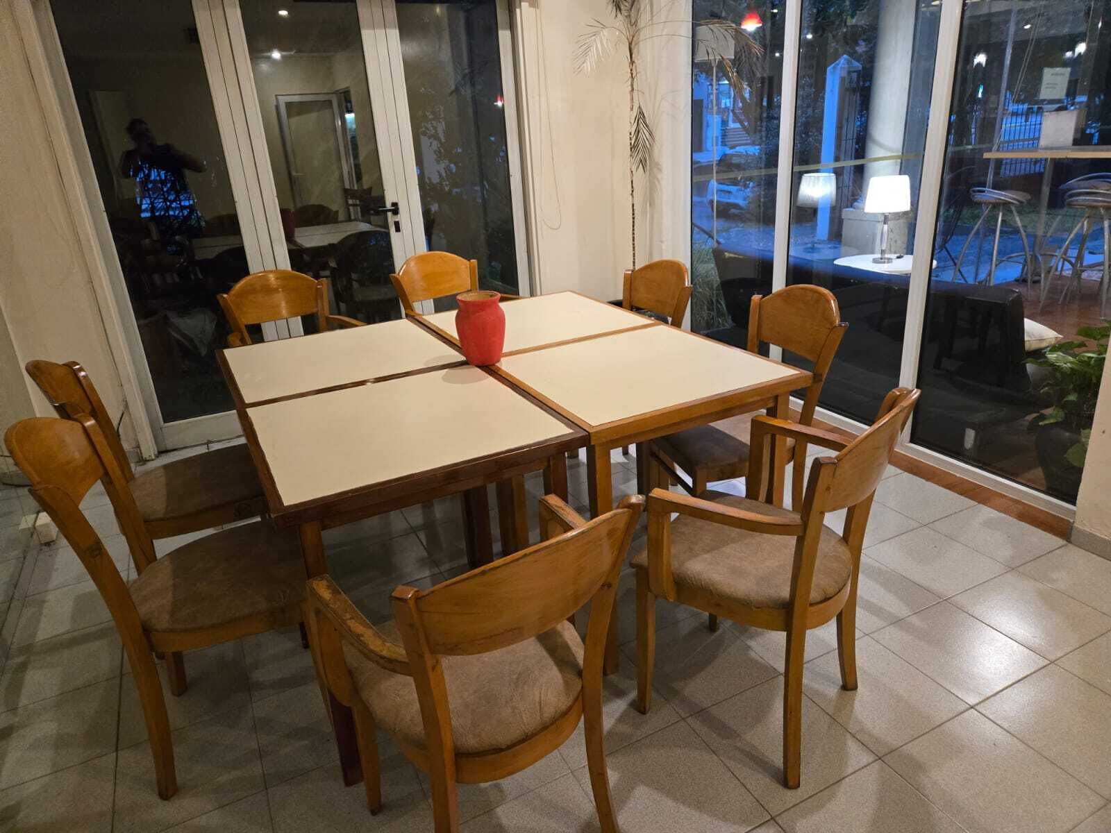 Un coin repas avec une table et des chaises, un vase rouge et une vue à travers les portes vitrées.
