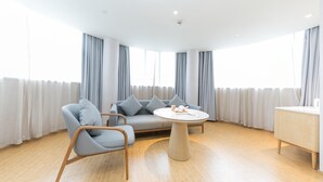 Un salon moderne comprenant un canapé, deux fauteuils, une table basse ronde et un meuble en bois.