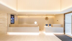Un espace d’accueil moderne comprenant un comptoir de réception en bois, un écran numérique et un guichet d’accueil.