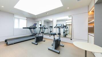 Ein modernes Fitnessstudio mit Laufbändern, Crosstrainern und einem großen Spiegel.
