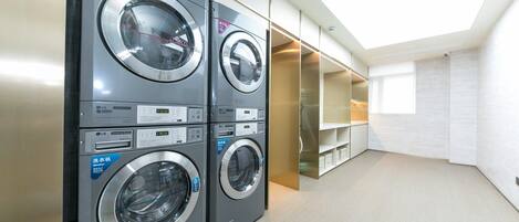 A laundry room with four LG washing machines, a skylight, and built-in storage cabinets.