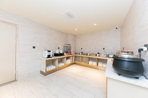 Cozinha moderna com ilha central, eletrodomésticos embutidos e uma panela preta grande.