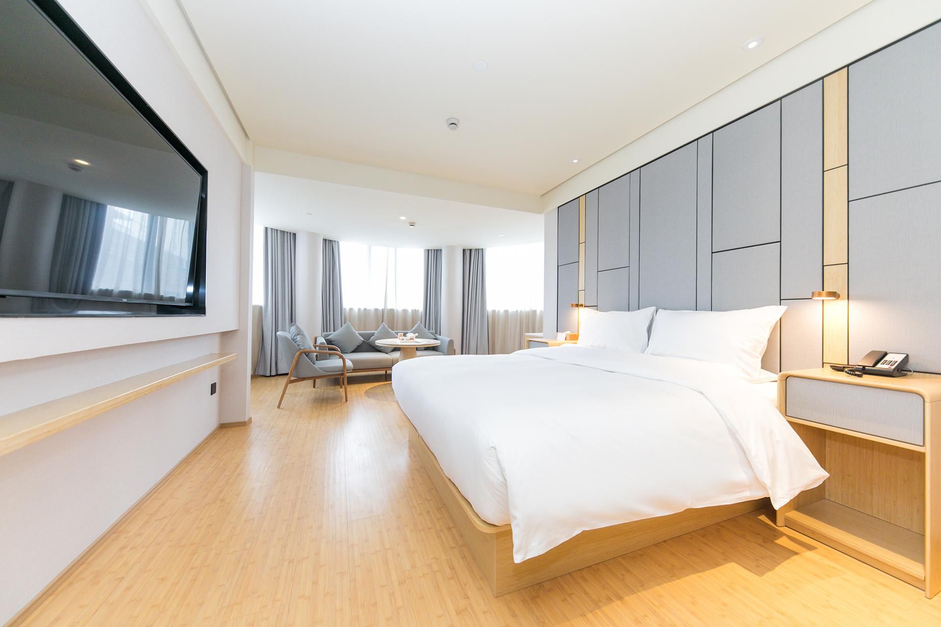 Ein Hotelzimmer mit einem großen Bett, einem Fernseher, einem Schreibtisch und einem Sessel.