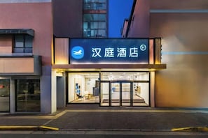 A hotel entrance with a sign in a foreign language, a glass door, and a paved walkway. - HanTing Hotel (Shanghai Xizang North Road Subway Station) (Shanghai)