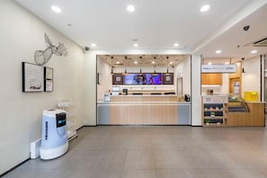 Un interior moderno con un mostrador de recepción, pantallas digitales y una estación de café.