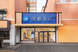A hotel entrance with a blue sign, glass doors, and a visible interior with seating. - HanTing Hotel (Shanghai Xizang North Road Subway Station) (Shanghai)