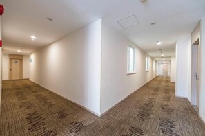 A long, narrow hallway with carpeted flooring and white walls. - HanTing Hotel (Shanghai Xizang North Road Subway Station) (Shanghai)