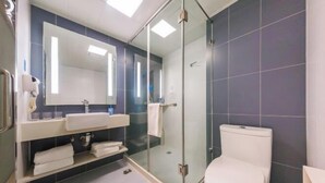 Ein modernes Badezimmer mit Duschkabine aus Glas, einer weißen Toilette und einem Waschtisch mit Spiegel und Handtuchhalter.