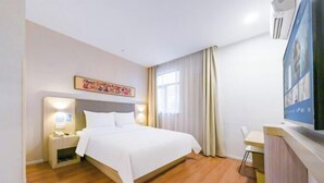 Ein Hotelzimmer mit Bett, Nachttisch, Lampe und Schreibtisch mit Stuhl.