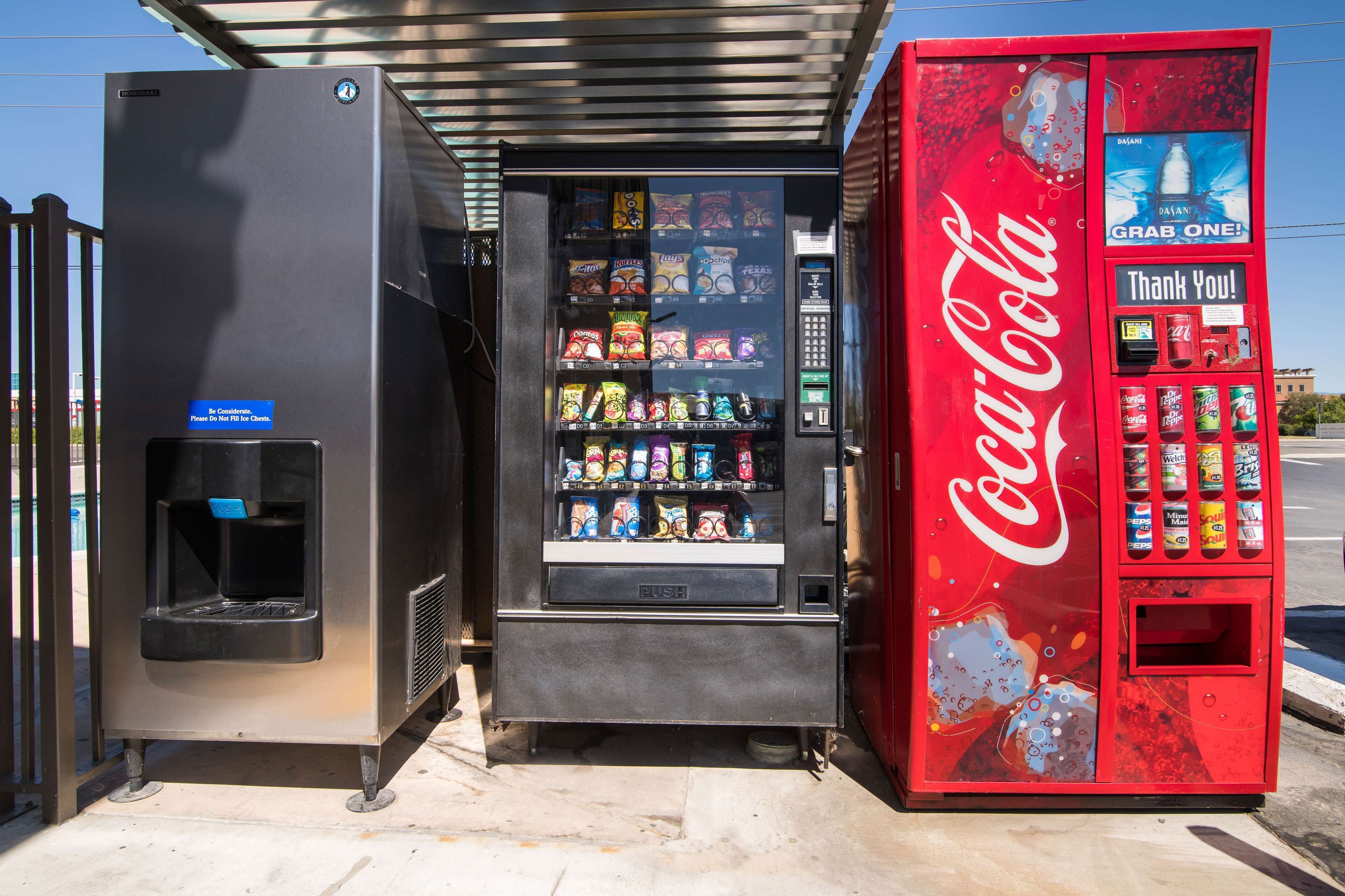 Un distributeur automatique orné du logo Coca-Cola, muni d’un point d’eau et proposant une variété de collations.