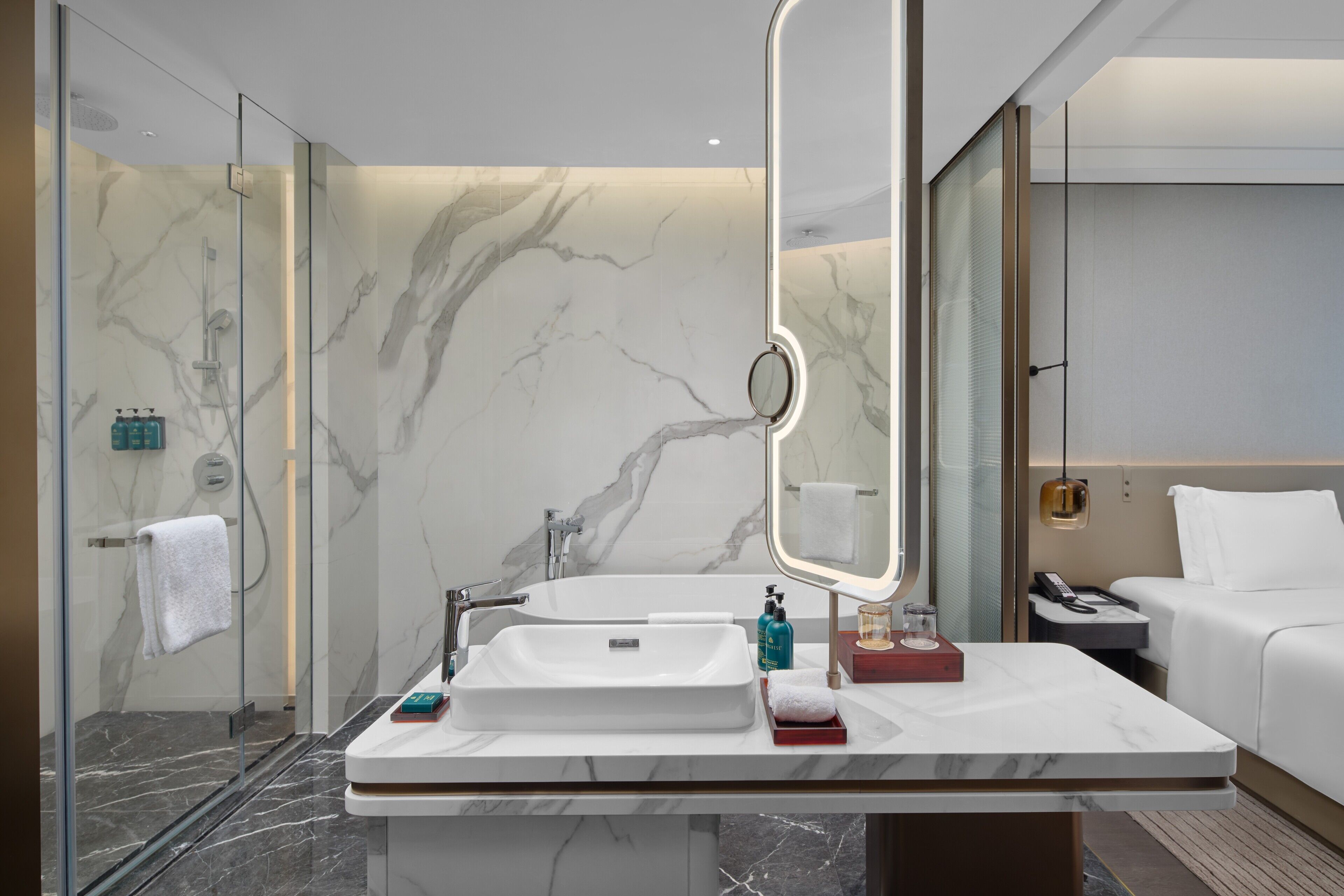 Un baño moderno con un espejo grande, un lavamanos blanco y una ducha con mampara de vidrio.