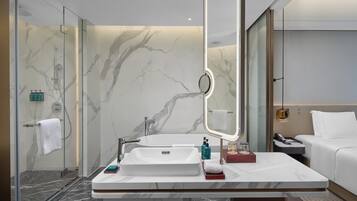 Un baño moderno con un espejo grande, un lavamanos blanco y una ducha con mampara de vidrio.