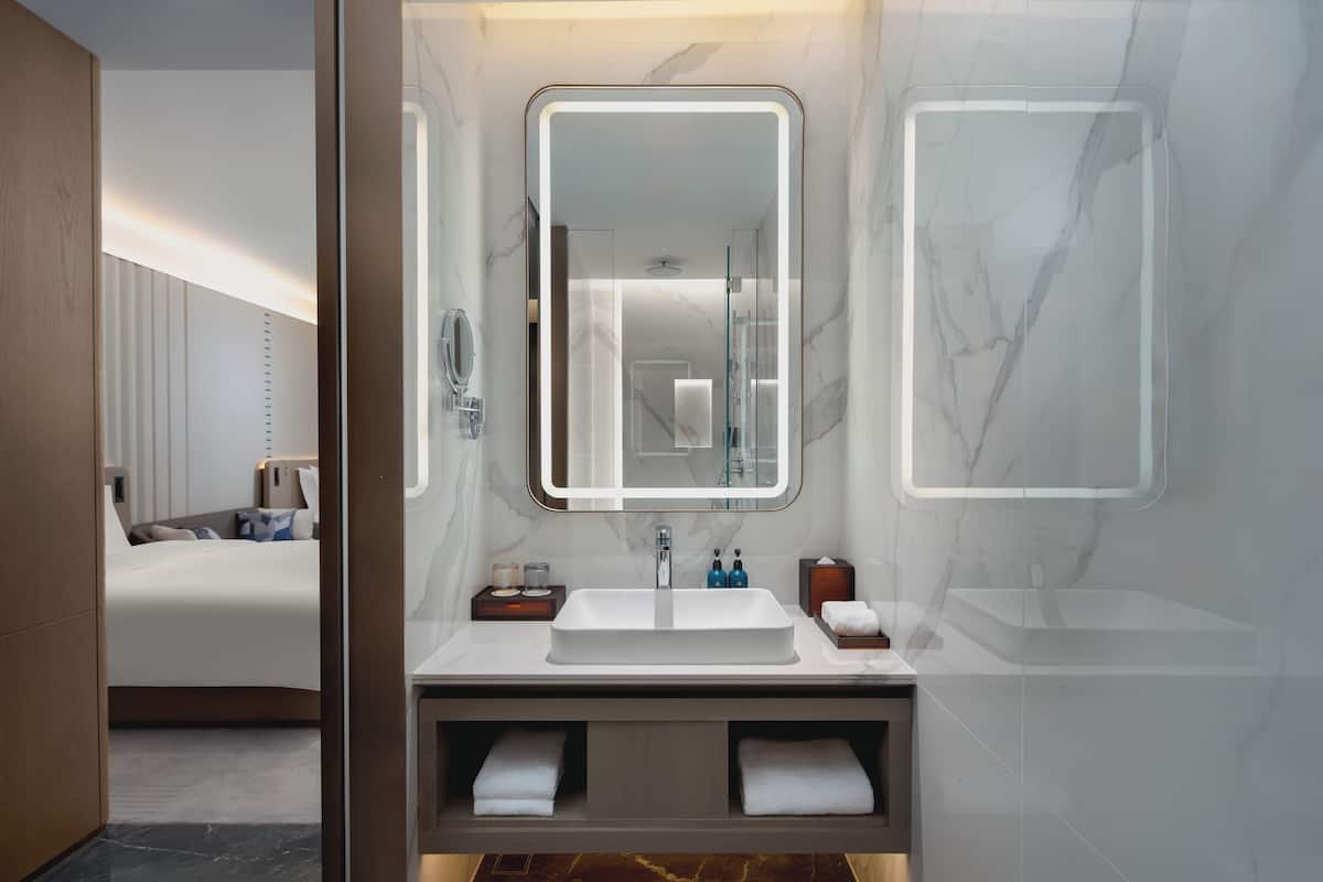 Features a sleek sink, matching vanity, and large mirror in a minimalist space with clean lines.