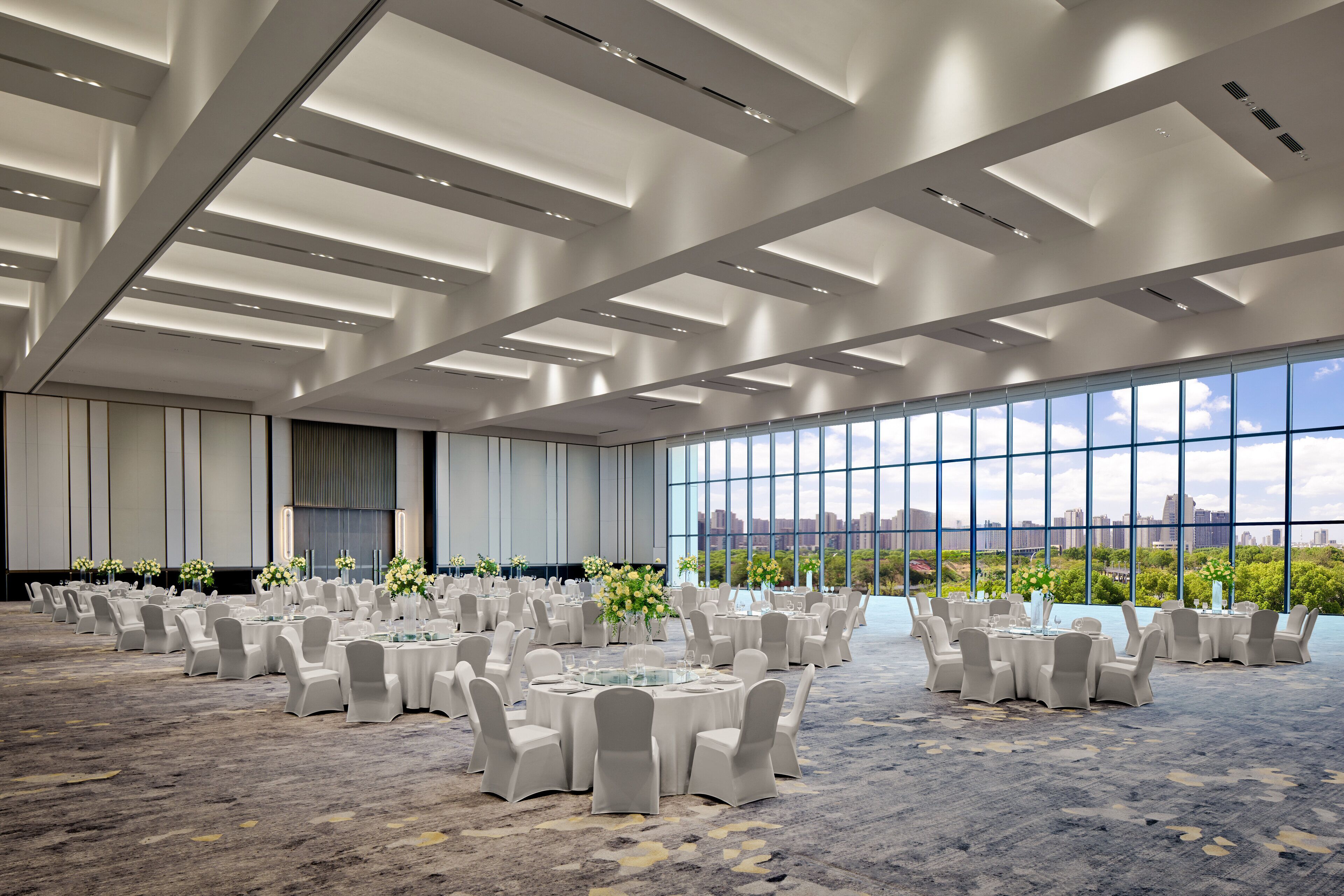 A large conference room with round tables and chairs, large windows, and a cityscape view.