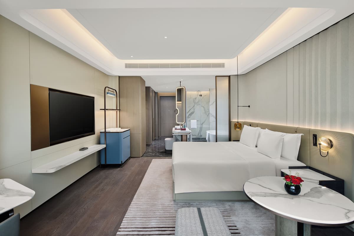 Relax in a serene space with a large bed, flat-screen TV, and a desk for work.