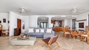 A spacious living room with a grey sofa, a coffee table, and a dining area with a wooden table and chairs. - Villa Mumbai (Lowlands)