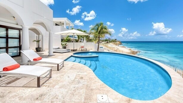 A poolside area with lounge chairs and a view of the ocean. - Villa Mumbai (Lowlands)