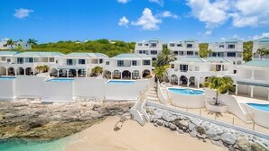 A resort with multiple white buildings, each with a pool and a view of the beach. - Villa Mumbai (Lowlands)