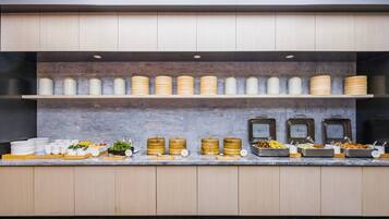 Una mesa de buffet con varios recipientes de comida y utensilios.