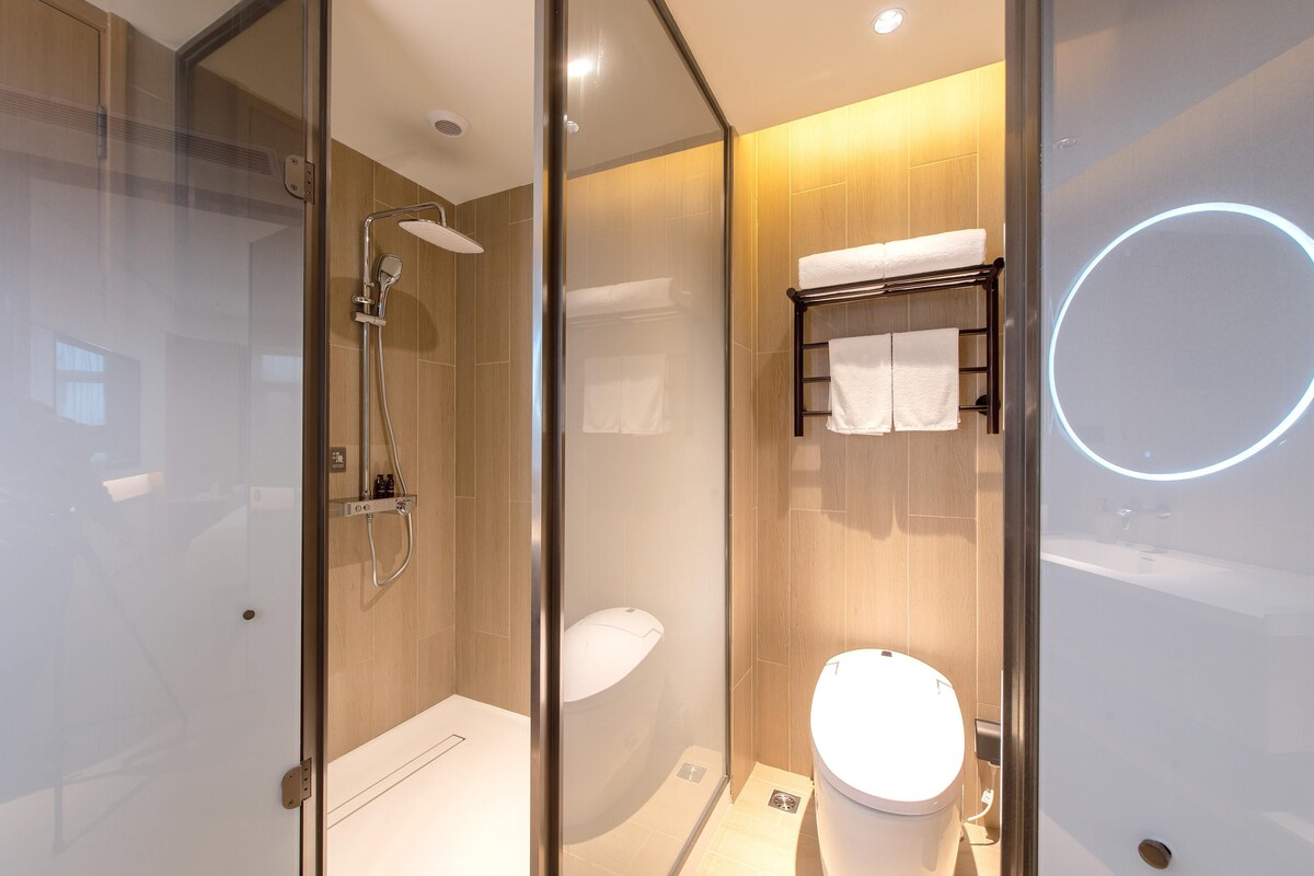 Un baño moderno con ducha de vidrio, inodoro y perchero para toallas.