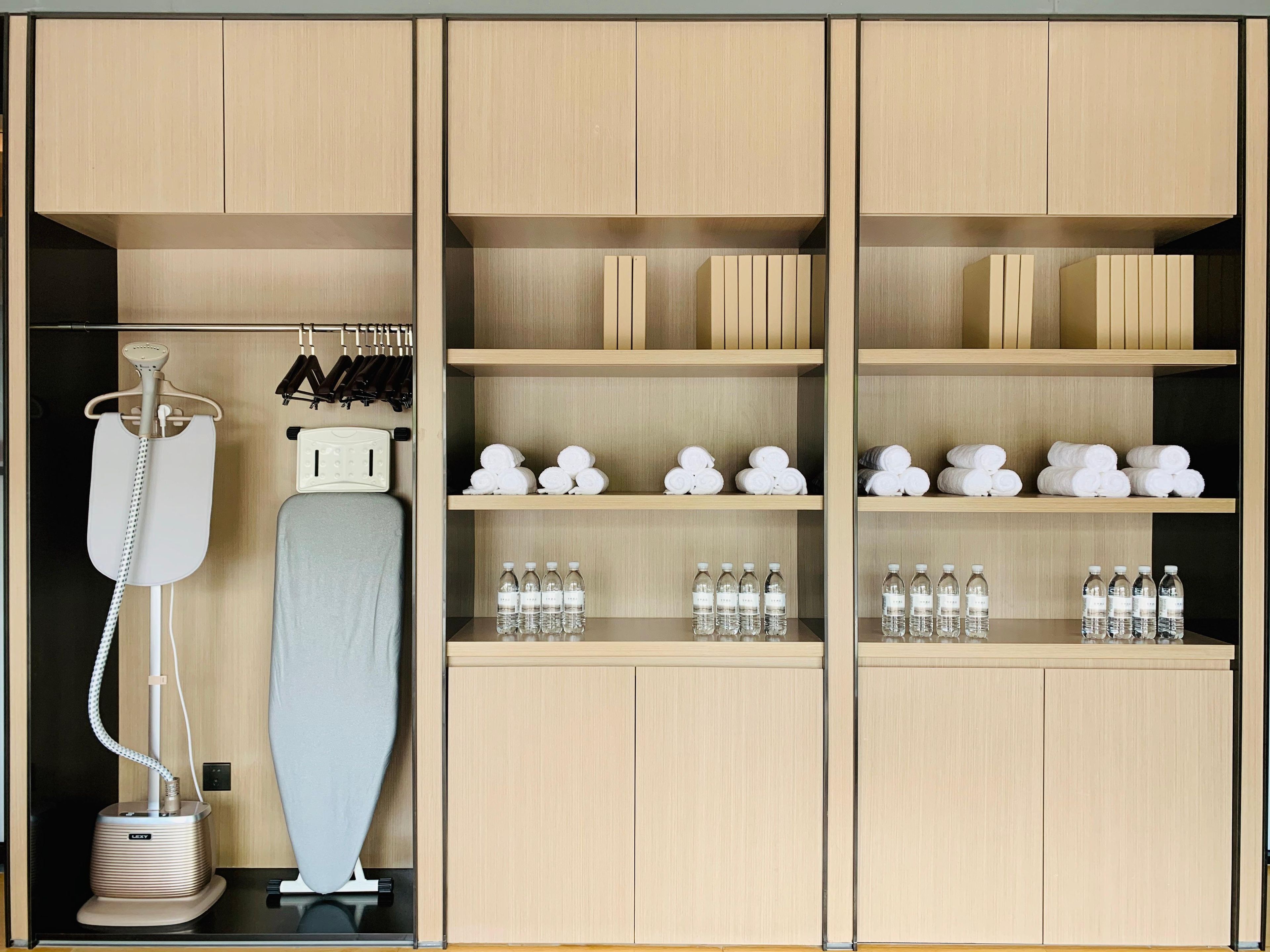 A hotel room with a minibar, a hairdryer, and neatly arranged towels and toiletries.