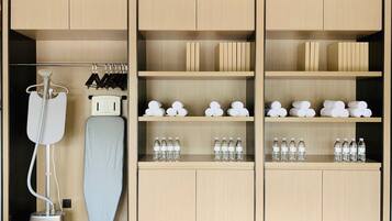 A hotel room with a minibar, a hairdryer, and neatly arranged towels and toiletries.
