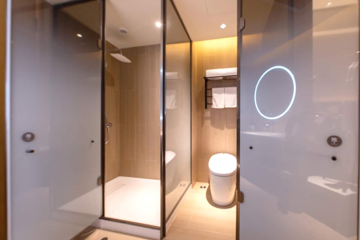 A modern bathroom with a glass shower enclosure, a white toilet, and a visible towel rack.