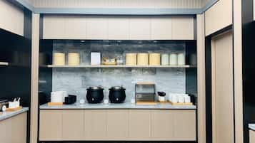 Uma cozinha moderna com armários de madeira, bancada de mármore e diversos eletrodomésticos.