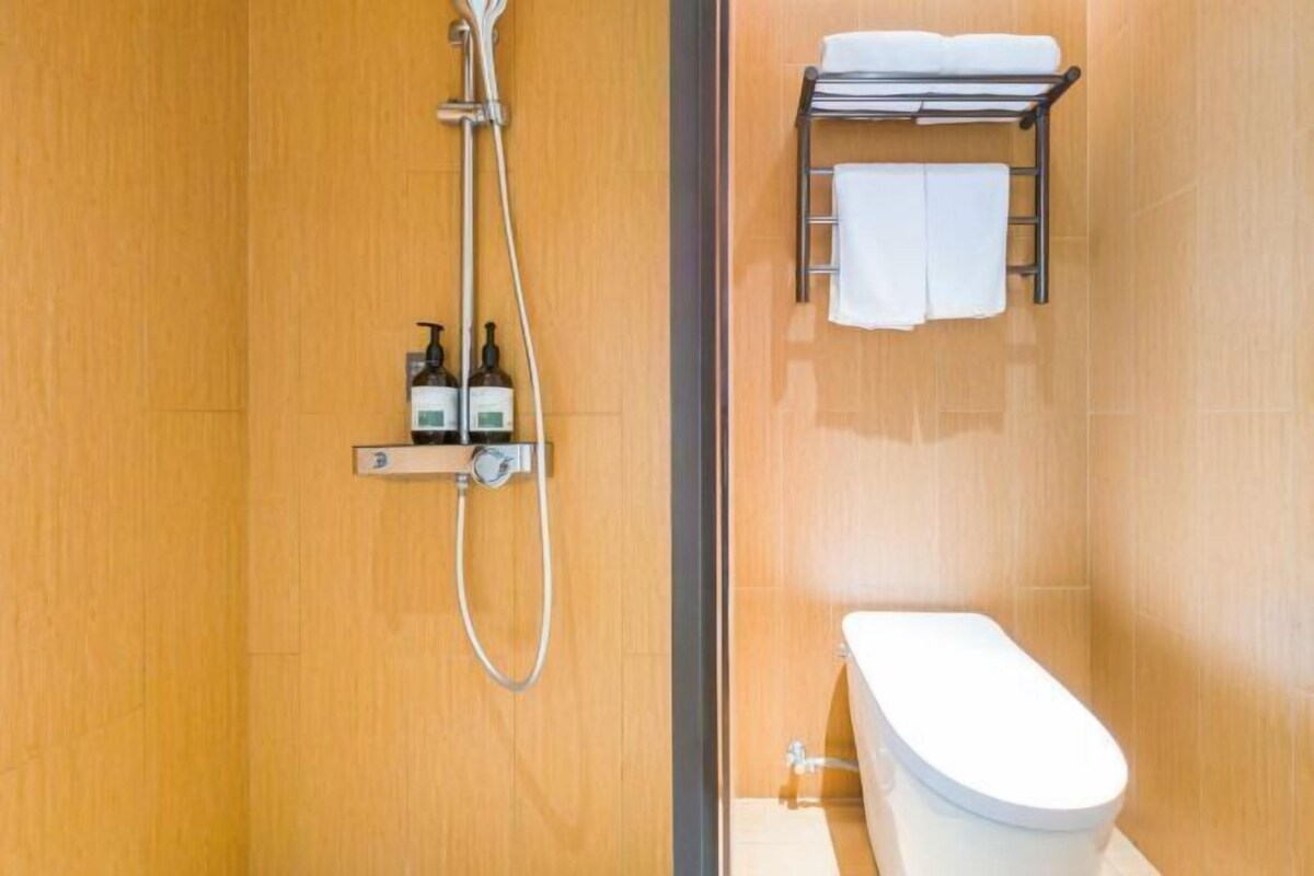 A bathroom with a shower, toilet, and towel rack.