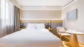 Una habitación de hotel moderna con una cama grande, mesitas de noche, una silla y una pequeña mesa.