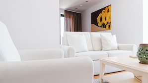 Un salon moderne avec un canapé blanc, une table basse en bois et un tableau représentant des tournesols accroché au mur.