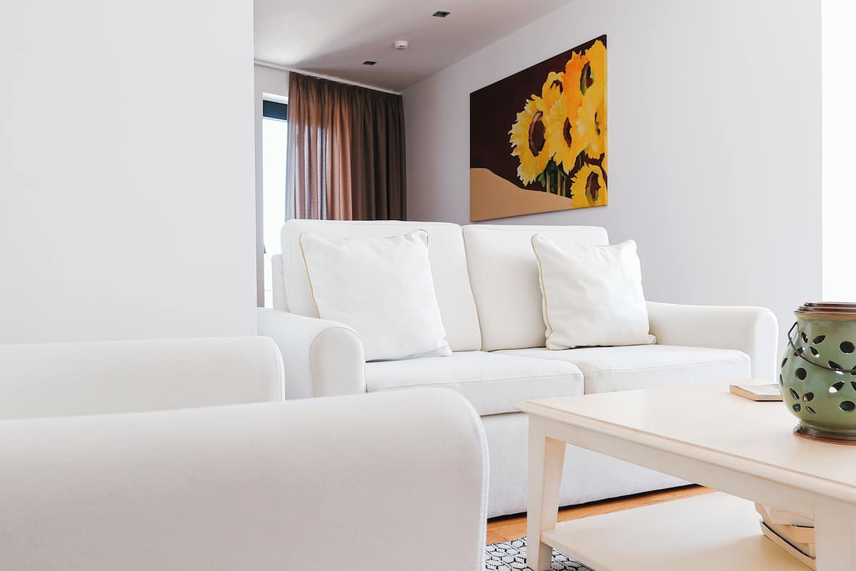 Una sala de estar moderna con un sofá blanco, una mesa de centro de madera y un cuadro de girasoles en la pared.