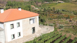 Un bâtiment en pierre, doté d’un toit recouvert de tuiles rouges, situé à côté d’un vignoble.