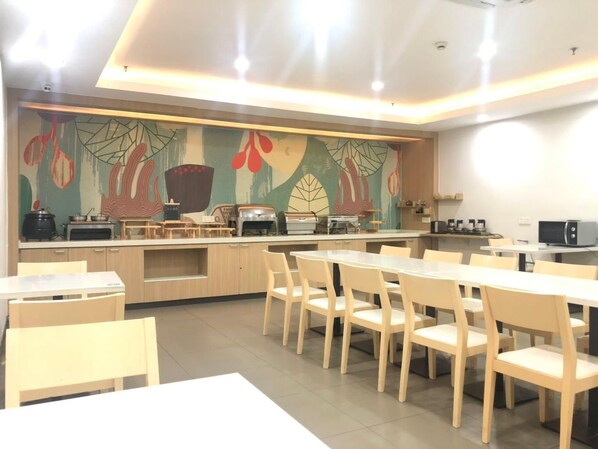A modern kitchen with a long counter, various appliances, and a mural on the wall. - Hanting Hotel Shanghai Macau Road (Shanghai)