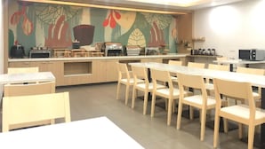 A modern kitchen with a long counter, various appliances, and a mural on the wall. - Hanting Hotel Shanghai Macau Road (Shanghai)